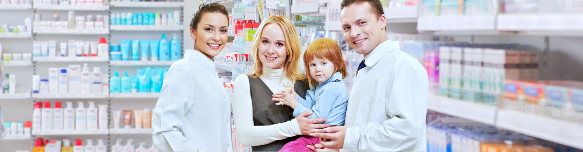 male and female pharmacist with a mother carrying her child smiling